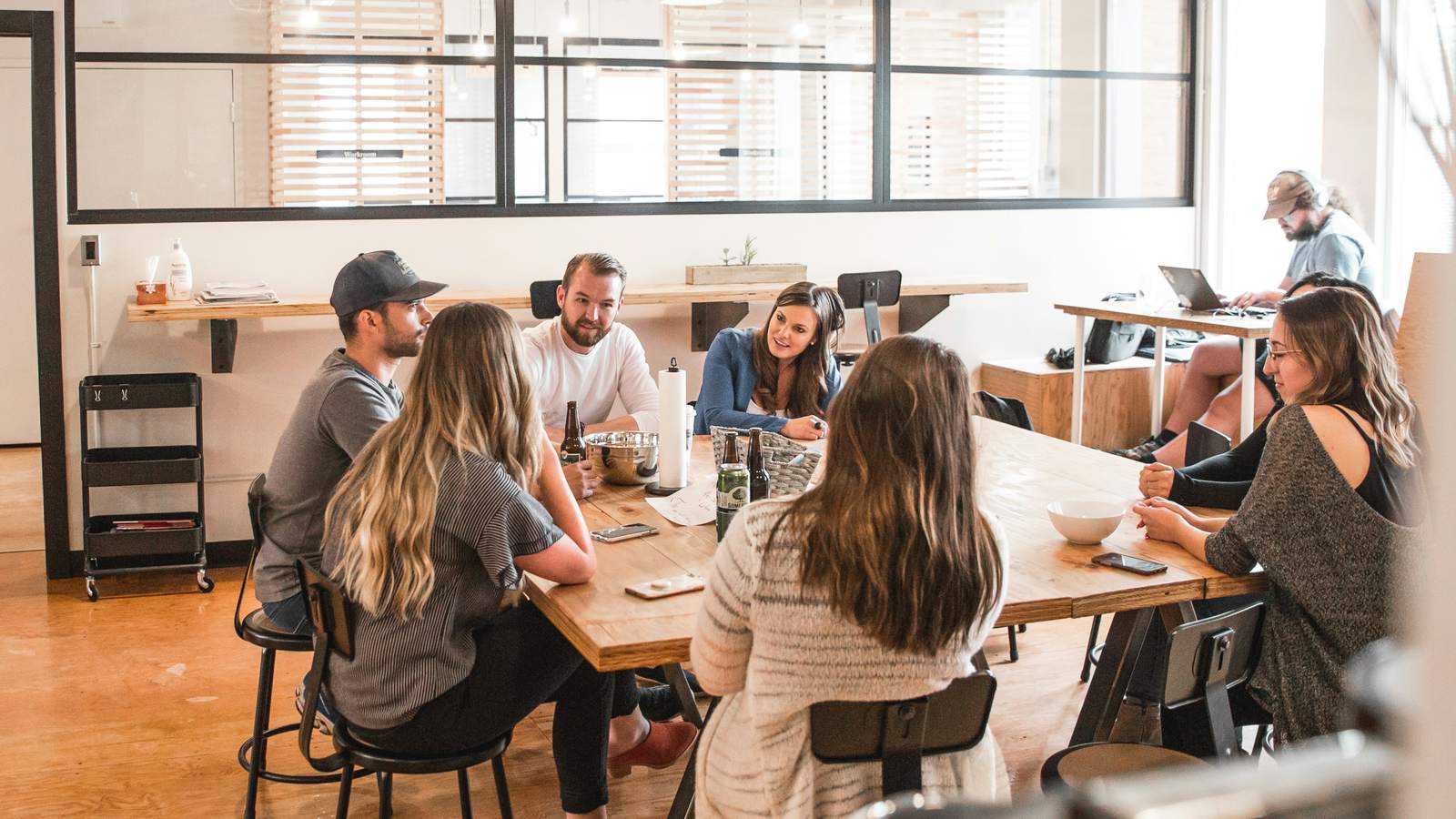 Une équipe réunie autour d’une grande table en bois, dans un bureau lumineux